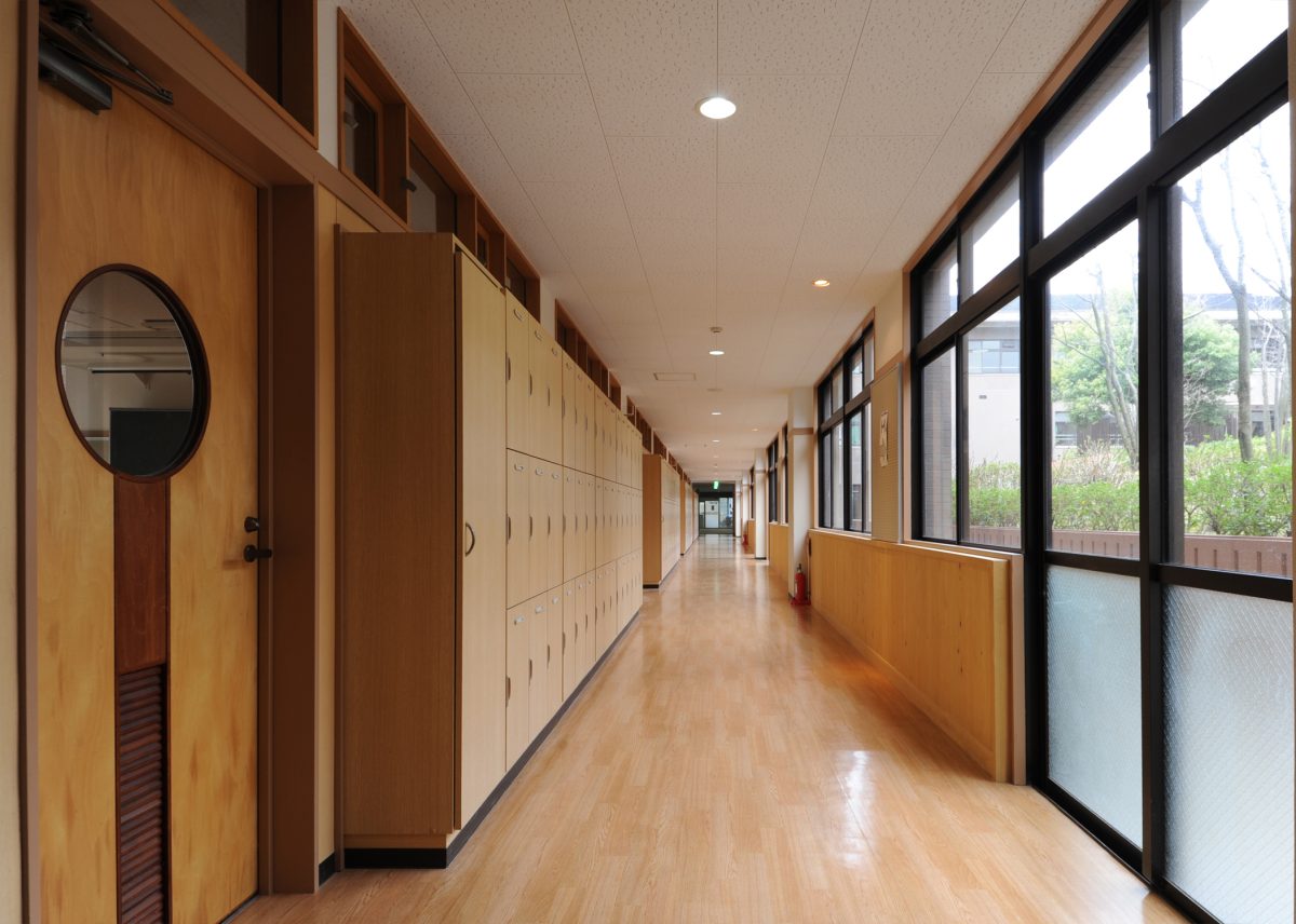窓を大きくとった開放感ある明るい廊下は、扉や腰壁などに木材を利用