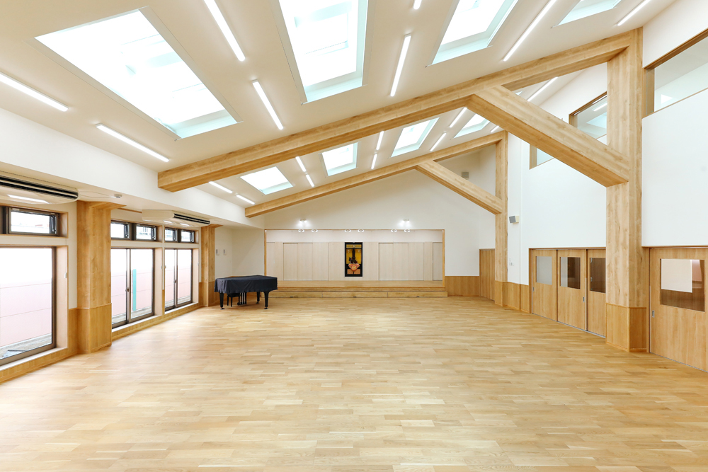 悪天候でも屋内でのびのび遊べるように、広さ154㎡、天井高6ｍという大空間を実現<br>勾配天井にはトップライトを設けて自然光を採り込み、明るさも確保<br>トップライトは日差しの強さに応じて、電動で日除けを開放することもできます