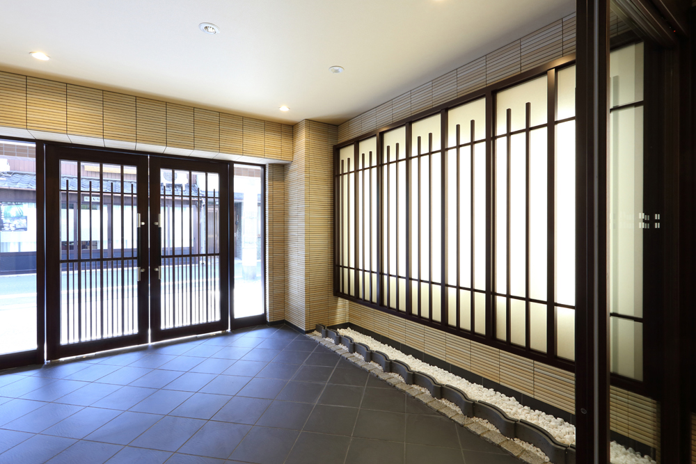 瓦と白玉砂利を入れ、障子格子と間接照明で凛とした表情のエントランスファサード