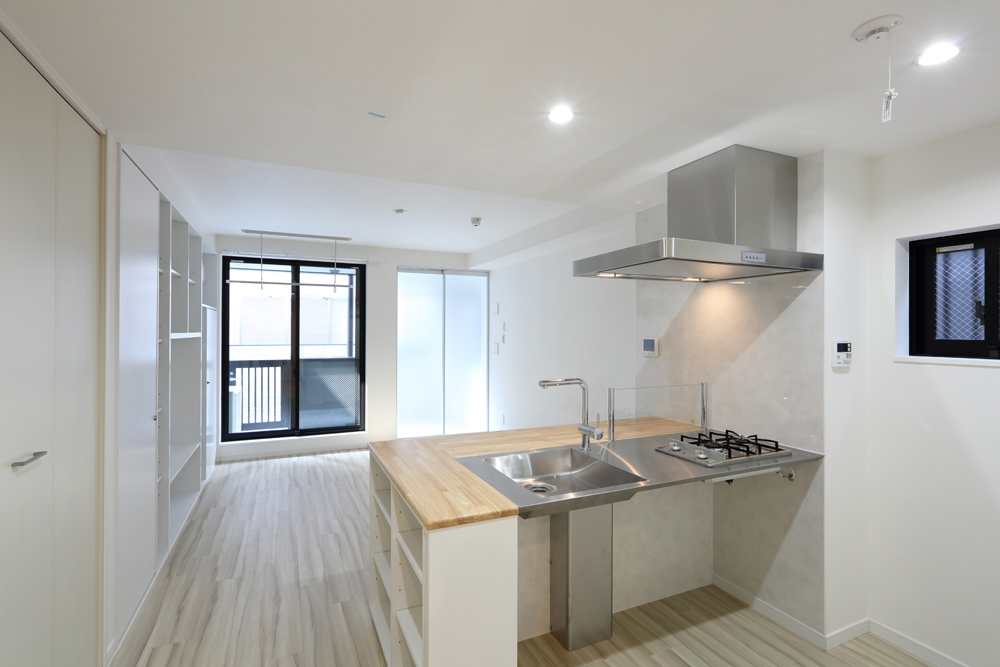 対面式でステンレスのスタイリッシュなキッチン。側面には収納棚を配置