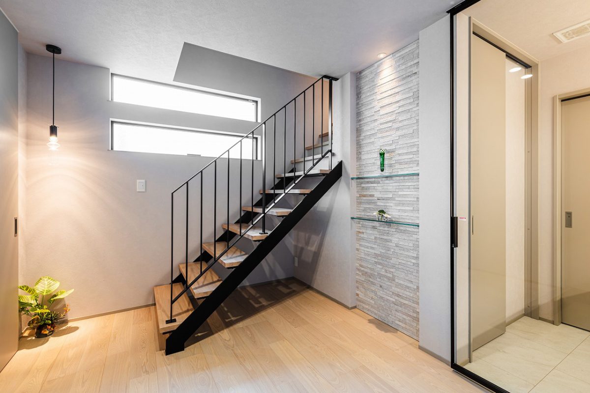 階段横の床から天井まで伸びるニッチにはタイルをあしらい、ガラス棚を設けました。ディスプレイに光を落とし、上品な空間に仕上げます。<br>1階に水まわりを集約することで生活動線が短縮され、日々の暮らしがスムーズに。玄関から洗面へと直接つながる動線により、帰宅してすぐに手洗いが可能です。