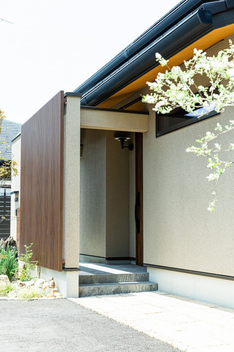 落ち着いた外観色とアクセントに設けた木目格子は、玄関の中が見えないように配置することでプライバシーに配慮しています。