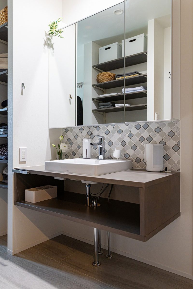 洗面台はカウンターと一体型になっており、デザイン性をもたせました。<br>ミラーキャビネットで日用品もすっきりと整理。サイドにはオープン棚を設け、タオルや洗剤などの収納に便利です。