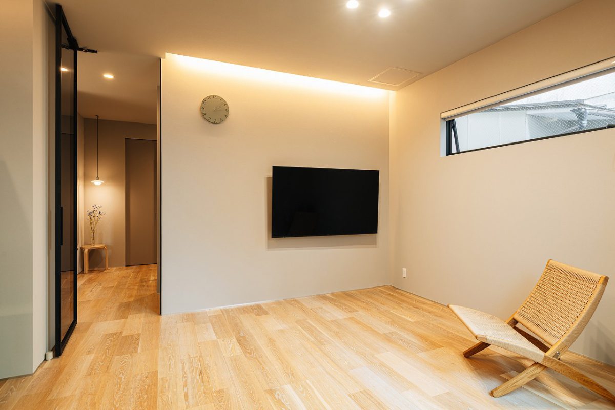 リビング空間のテレビ周りにはボードを設けず、シンプルに美しく整えました。<br>玄関とLDKをつなぐハイドアはガラス戸にすることで、すっきりとした印象に。