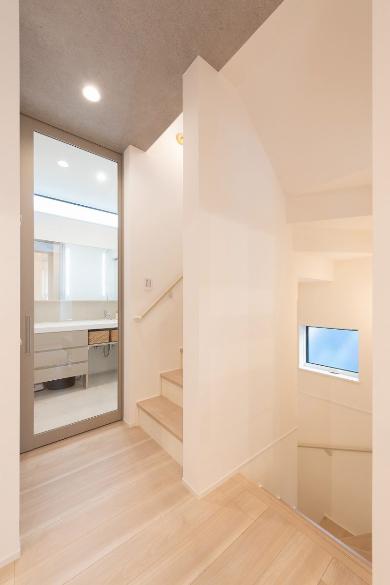 天井まで高さのあるガラス建具を巧みに活用することで抜け感を演出し、自然光が効果的に取り込まれることで、全体的に明るく開放的な雰囲気が生まれています。シンプルでモダンなデザインが特徴で、淡い色合いの床材と白を基調とした壁面が、空間を柔らかく仕上げています。