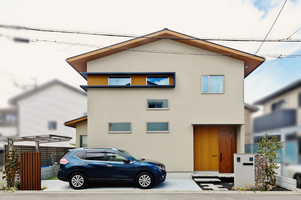 五条展示場をモチーフにした外観。モダンでシンプルなデザインが特徴です。明るいベージュの外壁と木目が調和し、温かみを感じさせます。窓まわりを囲む黒のフレームとのコントラストも際立っています。