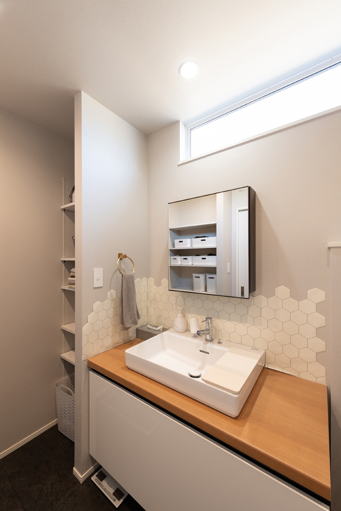 広々とした洗面台とたっぷりの収納を設けました。高窓からは自然光が降り注ぎます。