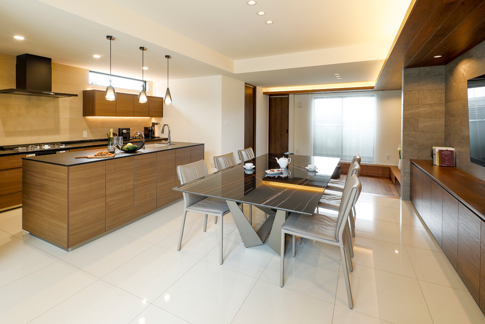 ダイニングキッチンには光沢感のある床タイルとウォルナット色のキッチンで高級感を演出。<br>また、タイルを随所にあしらい、間接照明の優しい光でさらにラグジュアリー感のある空間になりました。