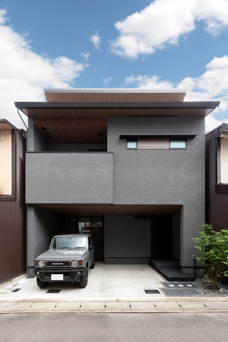 無機質な印象の存在感抜群の外観はグレーの塗り壁を採用。軒天に木のデザインを使用し、あたたかな雰囲気もプラス。エアコンの室外機や換気扇のフードカバーも表通りから見えないように配置しました。細部にわたりデザインを意識した仕上がりです。