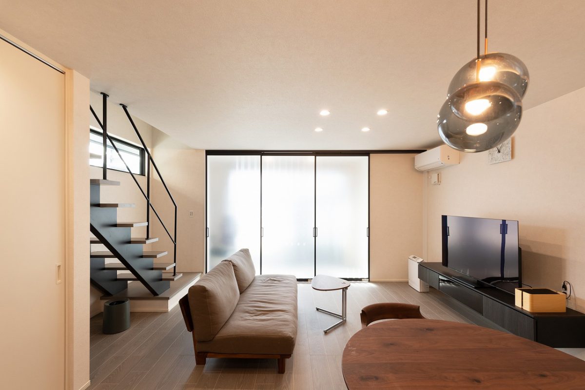 差し込む光の印影が美しいリビング空間。シックモダンなテイストに、くすみカラーをベースにしたインテリア。丸みを帯びたソファやテーブル、ガラスのペンダント照明を取り入れることで柔らかな印象になりました。