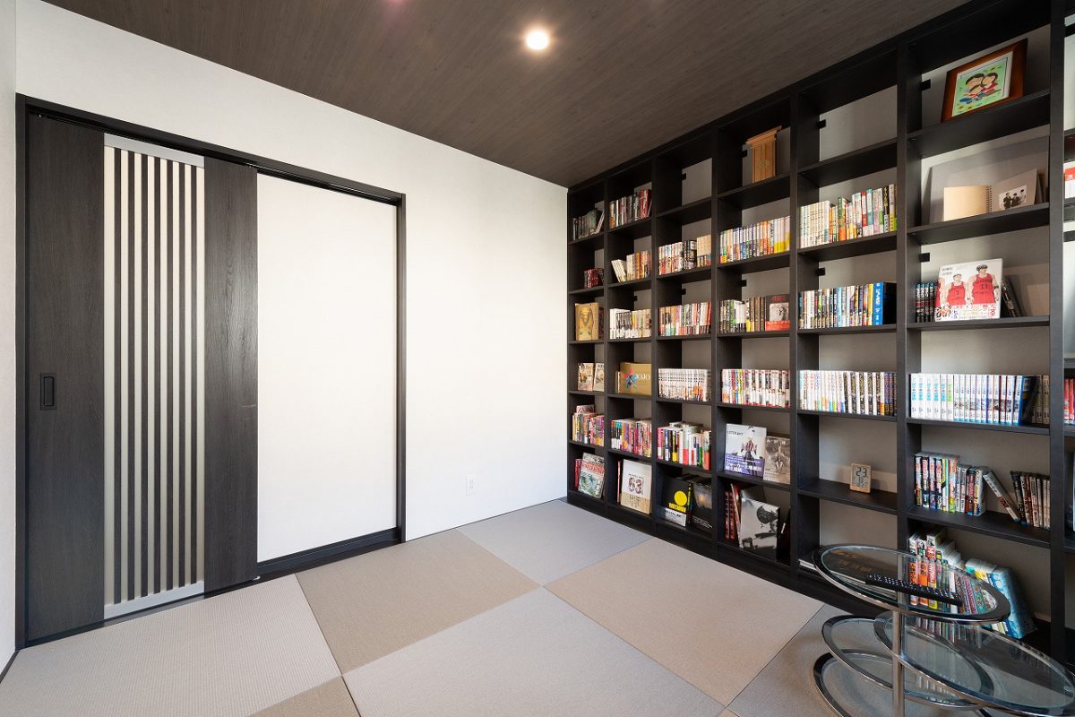 壁一面の造作棚が印象的な、多目的に使える洋和室。床には他の洋室と色味をそろえたグレーの畳を採用し、空間全体に統一感を持たせています。漫画や本、趣味のアイテムを並べることで、どこか心くすぐるような“好き”が詰まった空間に。