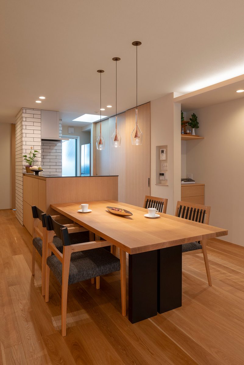 白と無垢材を基調にした端正なダイニングエリア。十分な収納力を備えたカップボードは扉で隠せるようにし、スッキリとした空間に。キッチン上部の天窓からは自然光が降り注ぎます。