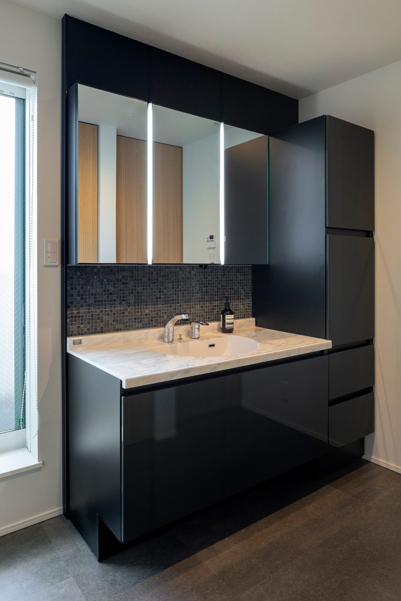 洗面脱衣室の洗面化粧台は黒でシックな印象に。収納力もしっかり確保しています。