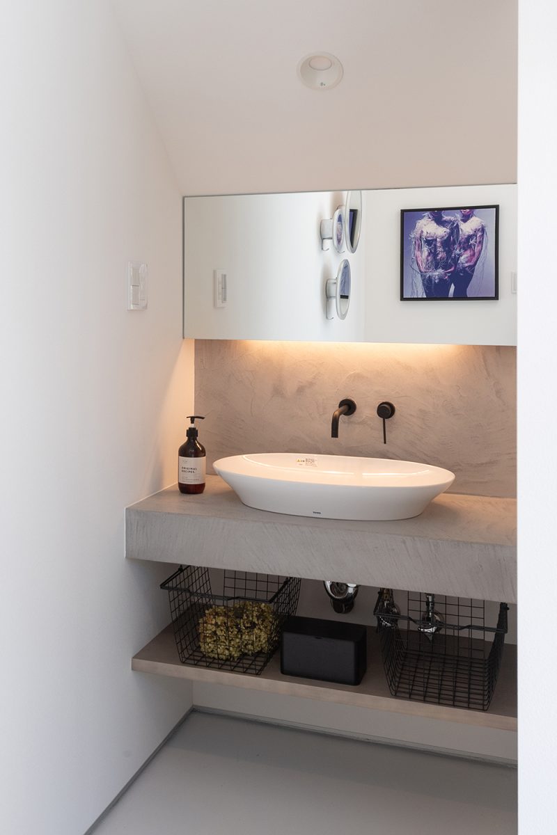 手洗いコーナーもコンクリート調のカウンター、壁に白いボウルを合わせすっきりとした印象に。鏡に映り込むものさえ絵になります。
