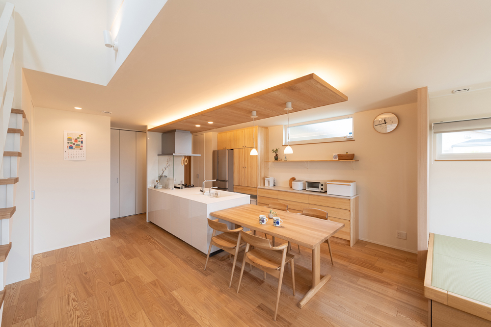 キッチンとダイニングは横並びに配置し、配膳もしやすいプランニングです。板天井の高さを下げ、間接照明を取り入れることで、空間にメリハリを付けました。