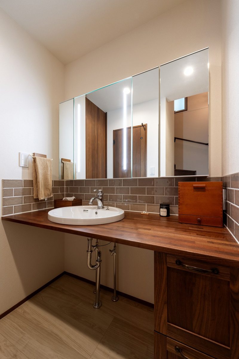 無垢の木を使った洗面台。タイルが壁面を飾り、空間のアクセントになっています。幅広い洗面台は、朝の準備をゆったりと行える快適なデザインになっています。