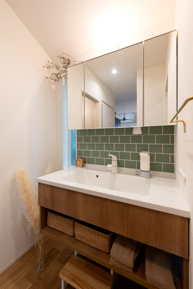 洗面台はフロートタイプで3面鏡の間に施した個性的な色のタイルが扉の木目ととても合い、すっきりとナチュラルな雰囲気になりました。