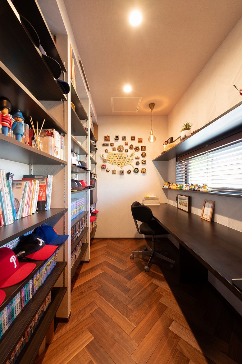 寝室に面する書斎は、ご主人の本やコレクションが並ぶプライベート空間です。部屋全体的に温かみのある色を採用し、カウンターと棚はダークブラウンで、ヘリンボーンの床材が特別感を与えます。