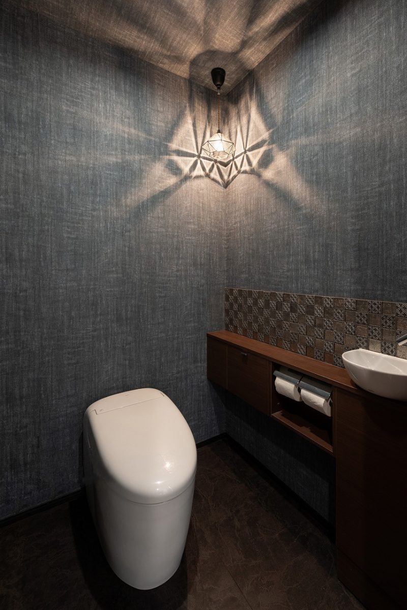 トイレは深い色調で統一。アクセントタイルと柔らかな照明が、落ち着いた空間を引き立てています。