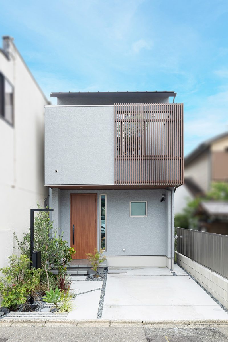 グレートーンを基調に、木目をアクセントとして取り入れたグレイッシュモダンな住まい。外観はすっきりとした直線的なデザインでまとめました。<br>バルコニーの立ち上がり部分は、半分を縦格子にすることで、通りからの視線を程よく遮りながら、室内に光と風を取り込めるようにしています。